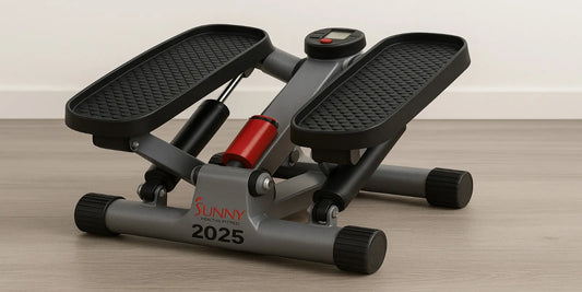 A compact Sunny Health & Fitness mini stepper with black pedals and red hydraulic cylinder, placed on a light wood floor against a neutral wall.